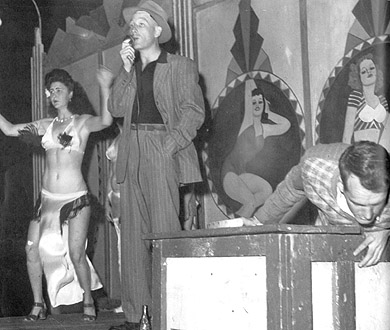 Fringes on a cooch dancer's costume fly as she and a talker work the crowd on a 1950s girl-show bally.