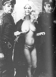 Bambi Lane is led away by police after streaking through the streets of Newark in 1974. After being taken from one police station to another, she was finally booked for indecent behavior.