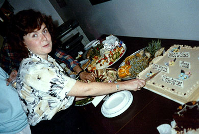 Fiona cutting a cake 'Best Wishes Fiona, Your Friend Hugh Gardner' at her farewell party from the Robin Gardner/Voce Housing Co-op. 1980s.